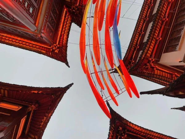 Low angle view of traditional Chinese buildings with red roofs and decorative hanging lanterns creating a festive atmosphere.