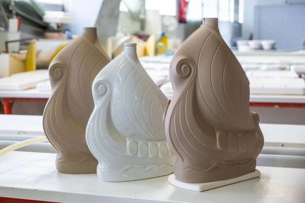 Three ceramic vases in a row on a white surface, two beige and one white, showcasing a decorative, minimalist design.