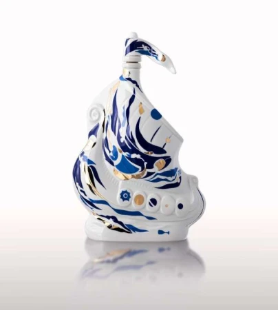 Decorative white porcelain ship with blue and gold accents, glossy finish, studio lighting, displayed on a reflective white surface.