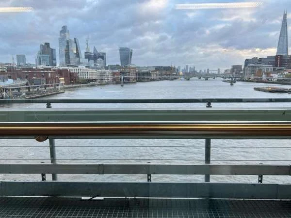 Cityscape of London, England, featuring the River Thames and modern architecture viewed from an elevated position on an overcast day.