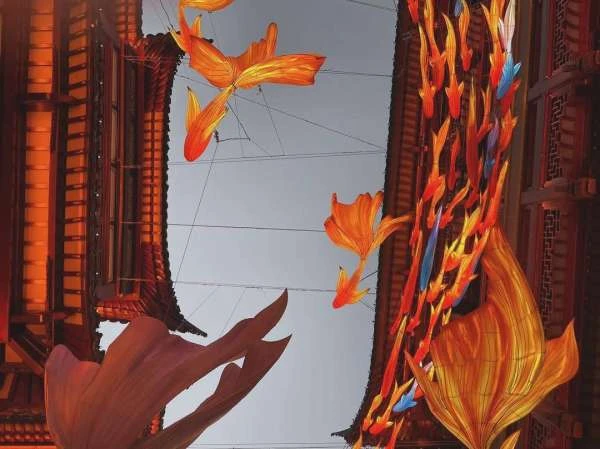 Intricate view from below showcases golden koi fish lanterns between traditional Chinese architecture, creating a festive, cultural display.