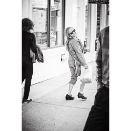 Monochrome street photography of smiling woman walking past storefront by Todd Norwood