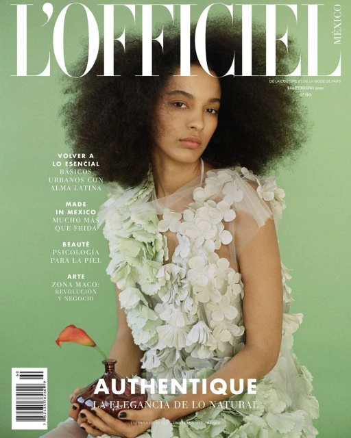 Magazine cover featuring a woman with afro hairstyle wearing a floral dress and holding a vase with a flower against a green backdrop.