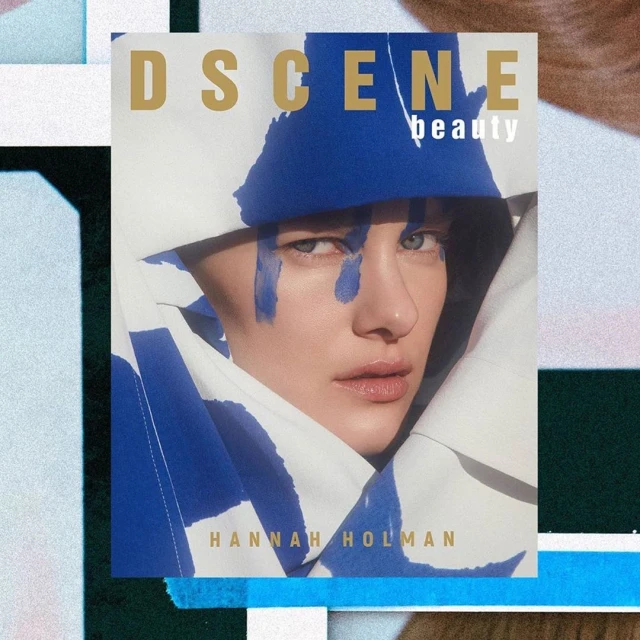 Magazine cover featuring a model with blue face paint wearing a white and blue jacket in a studio setting with geometric props.