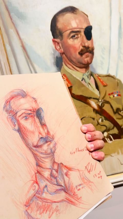 Artwork featuring a painted portrait of a man with an eyepatch alongside a red and blue sketch, displayed indoors.