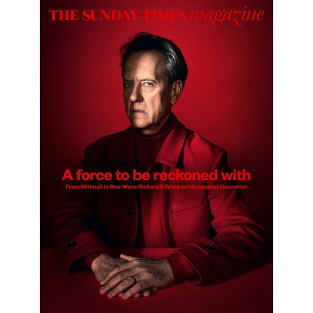 Portrait of Richard E. Grant on a red background for The Sunday Times Magazine, featuring the headline 'A force to be reckoned with'.