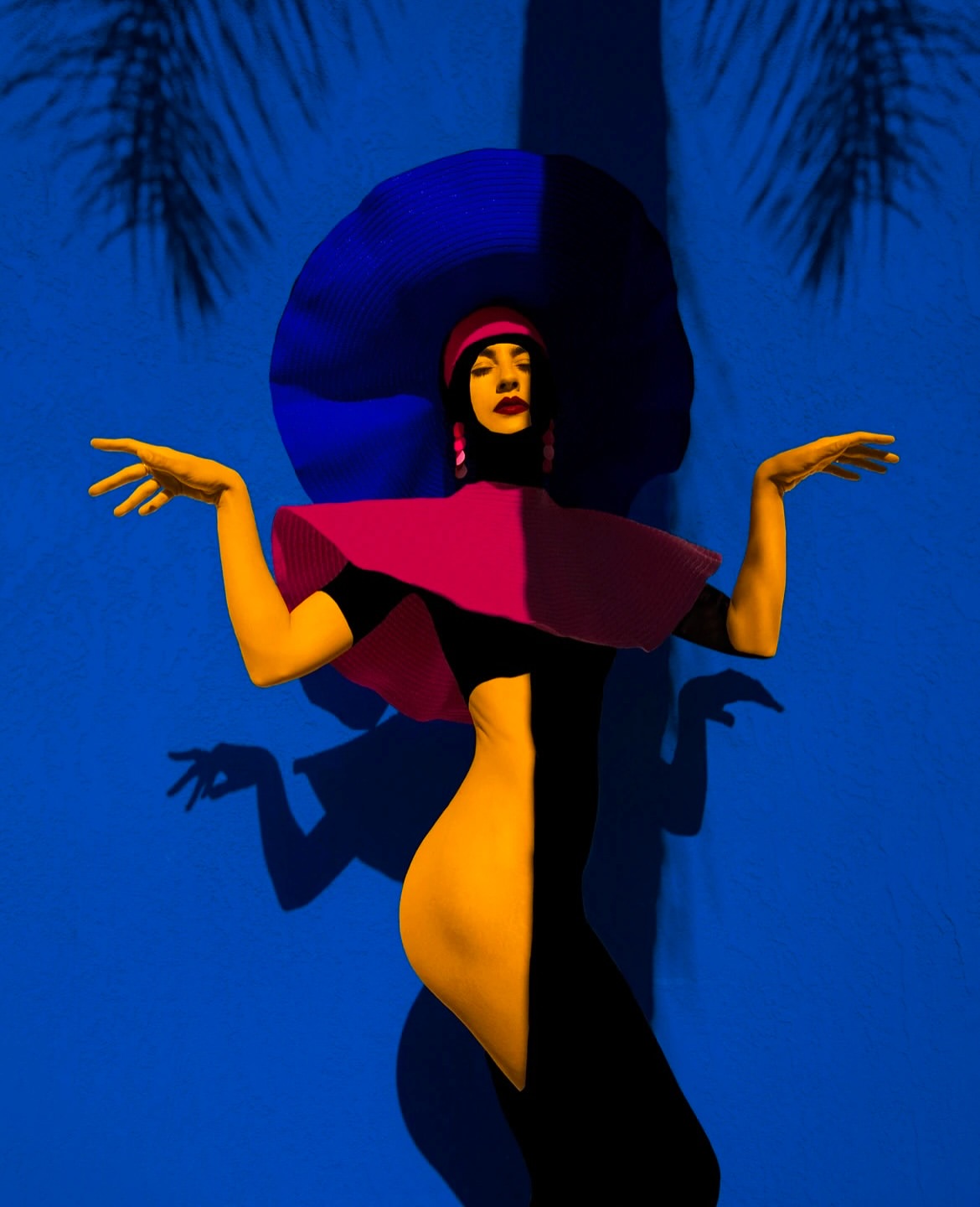 Stylized fashion portrait of a woman in a two-tone body suit, wide-brimmed hat, and palm tree shadows against a blue background.