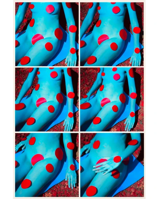 Abstract image of a blue body painted in the style of a cartoon, with red polka dots. A blue mat lies beneath the figure.
