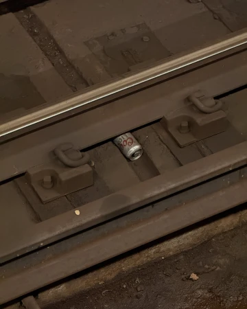 Discarded Coors Light beer can sits between the rails on a section of subway tracks, photographed in a medium, eye-level shot.