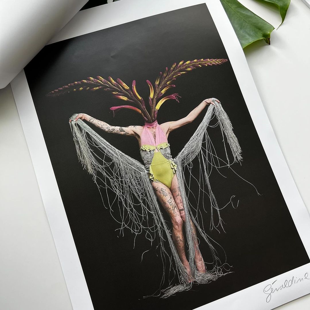 Surreal fashion photograph of a woman with a floral headpiece and draped fringe, set against a dark backdrop with a modern artistic feel.