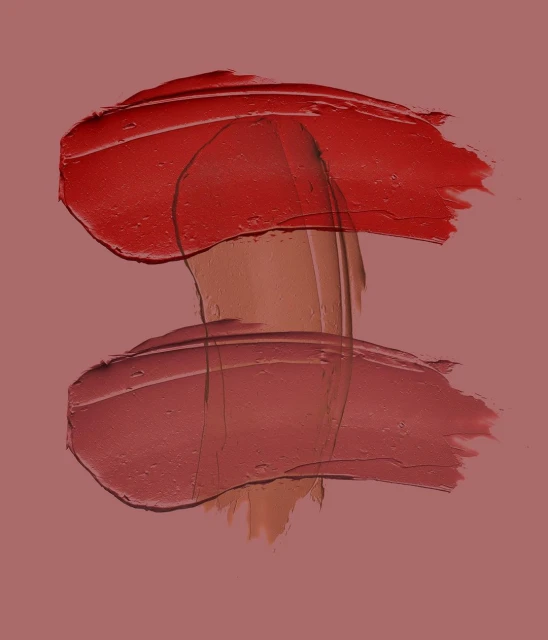 Abstract beauty shot of lipstick swatches in red and pink hues on a matching pink background, showcasing texture and color for beauty advertising.