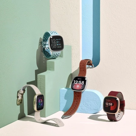 Four smartwatches with varied bands on stepped display. Fitness trackers show digital time against color block and gradient background.