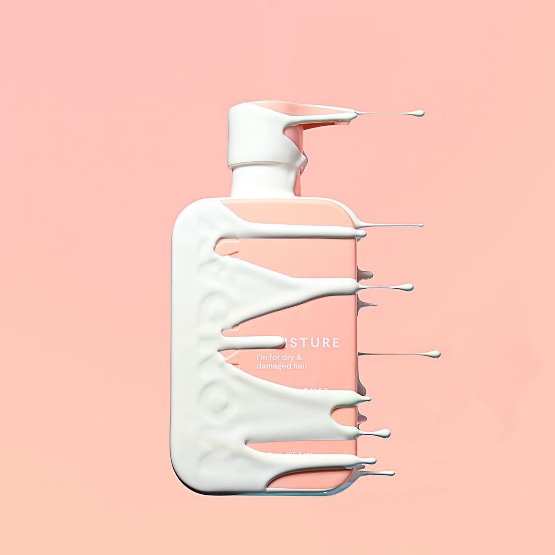 Product shot of a light pink bottle of hair product with white liquid dripping down the sides on a light pink background.