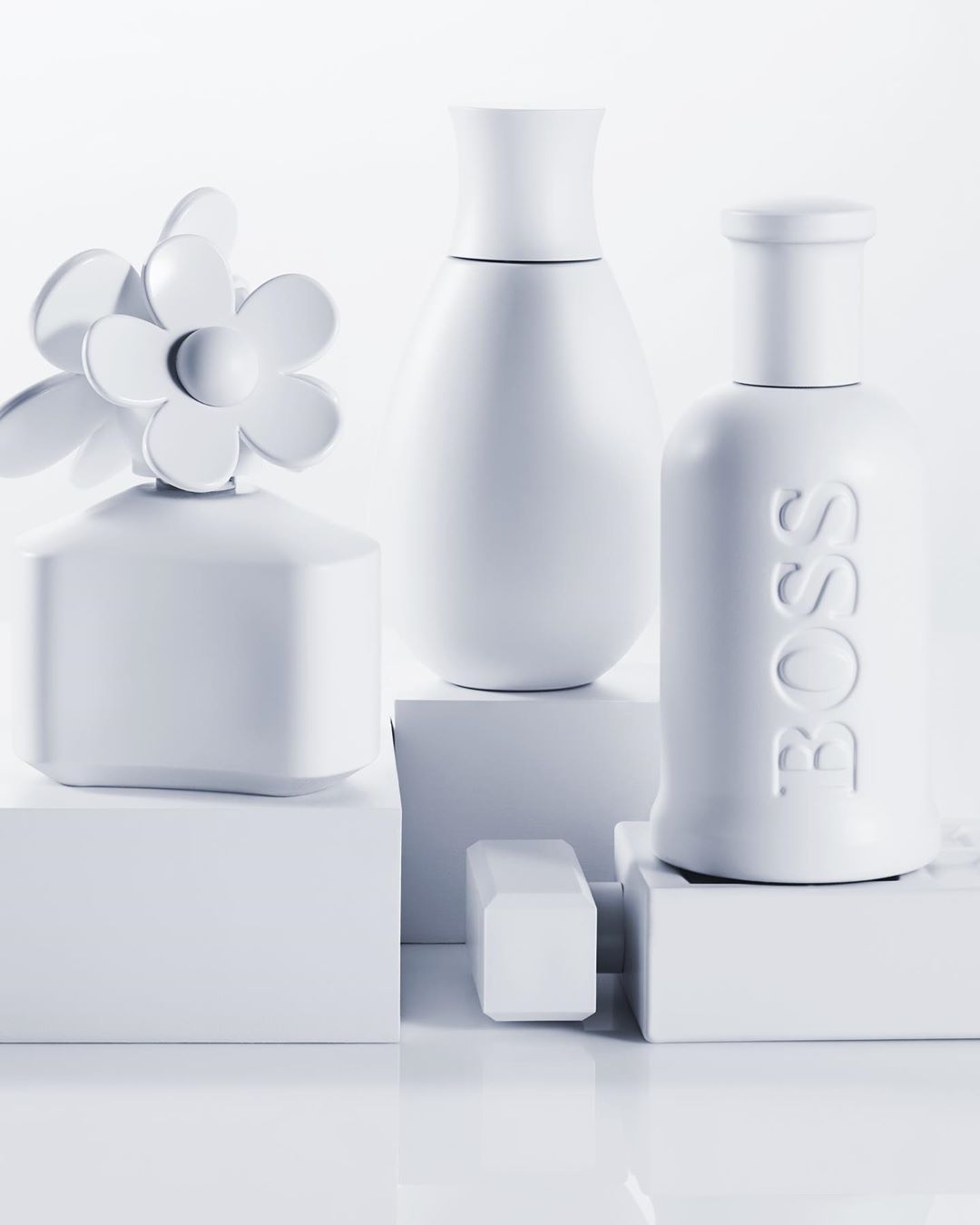 Still life arrangement featuring three different white perfume bottles displayed on small white platforms against a stark white backdrop. 