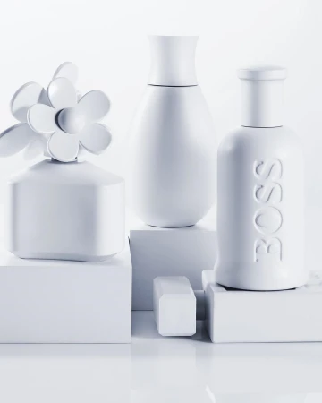 Still life arrangement featuring three different white perfume bottles displayed on small white platforms against a stark white backdrop. 