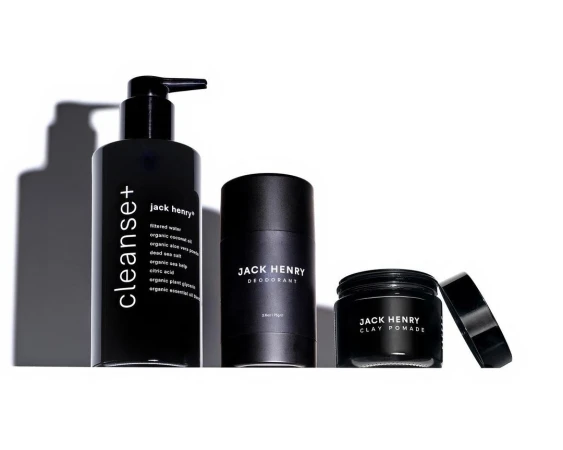 A trio of Jack Henry men's grooming products in black bottles against a bright white background, including cleanser, deodorant, and clay pomade.