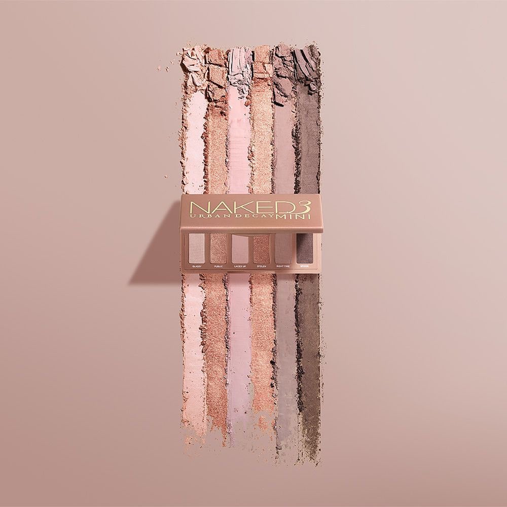 Naked 3 Urban Decay Mini eyeshadow palette displayed with color swatches in shades of nude, pink, beige and brown on neutral background.