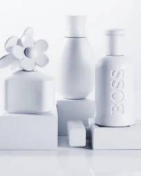Three white perfume bottles on tiered white pedestals against a clean white background