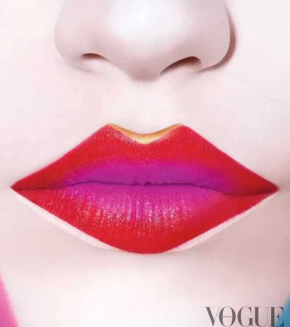 Close-up of a woman's lips with red and purple lipstick outlined in gold against pale skin, shot in a photo studio with Vogue logo.