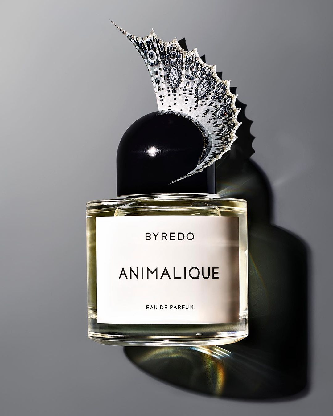 Studio shot of Byredo Animalique Eau de Parfum bottle with decorative butterfly element on grey background, perfume, cosmetics, beauty.