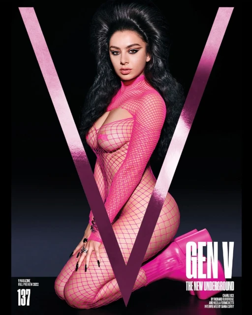 Magazine cover featuring a woman in a pink fishnet bodysuit and boots kneeling in front of a large pink V on a black background.