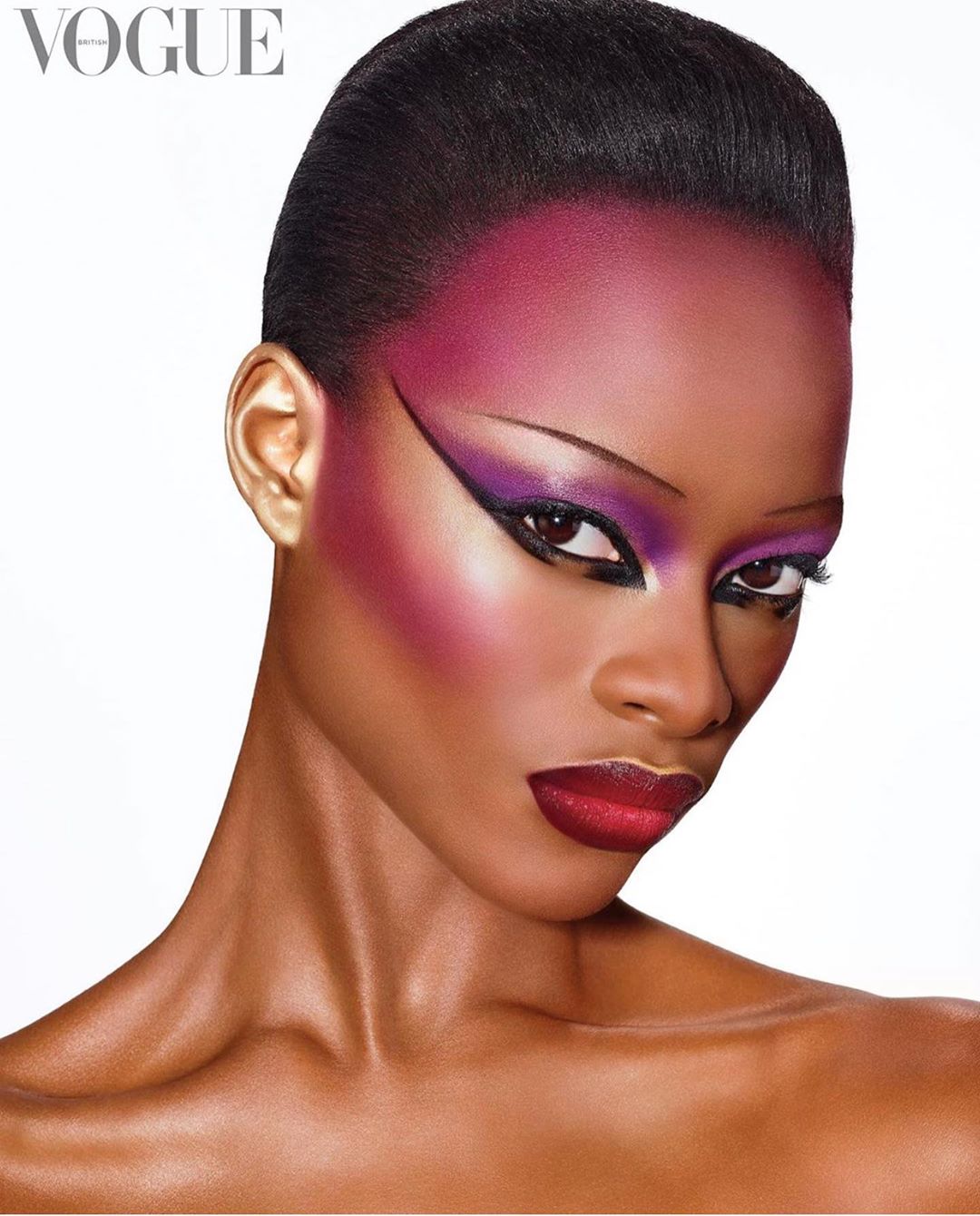 Close-up portrait of a woman with dramatic makeup and slicked-back hair against a clean white backdrop for Vogue magazine cover.