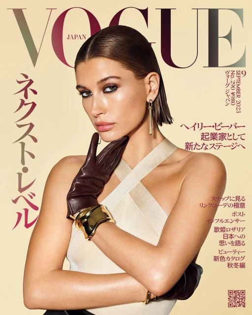 Vogue Japan cover featuring model Hailey Bieber wearing brown leather gloves and a gold cuff, with the Vogue logo prominently displayed.
