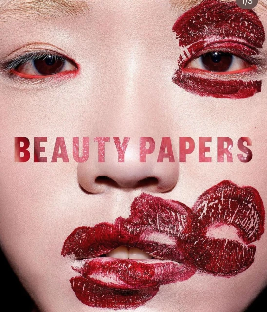 Close-up of a female face with smears of dark red lipstick around the eyes and mouth, with text overlay 'BEAUTY PAPERS'.