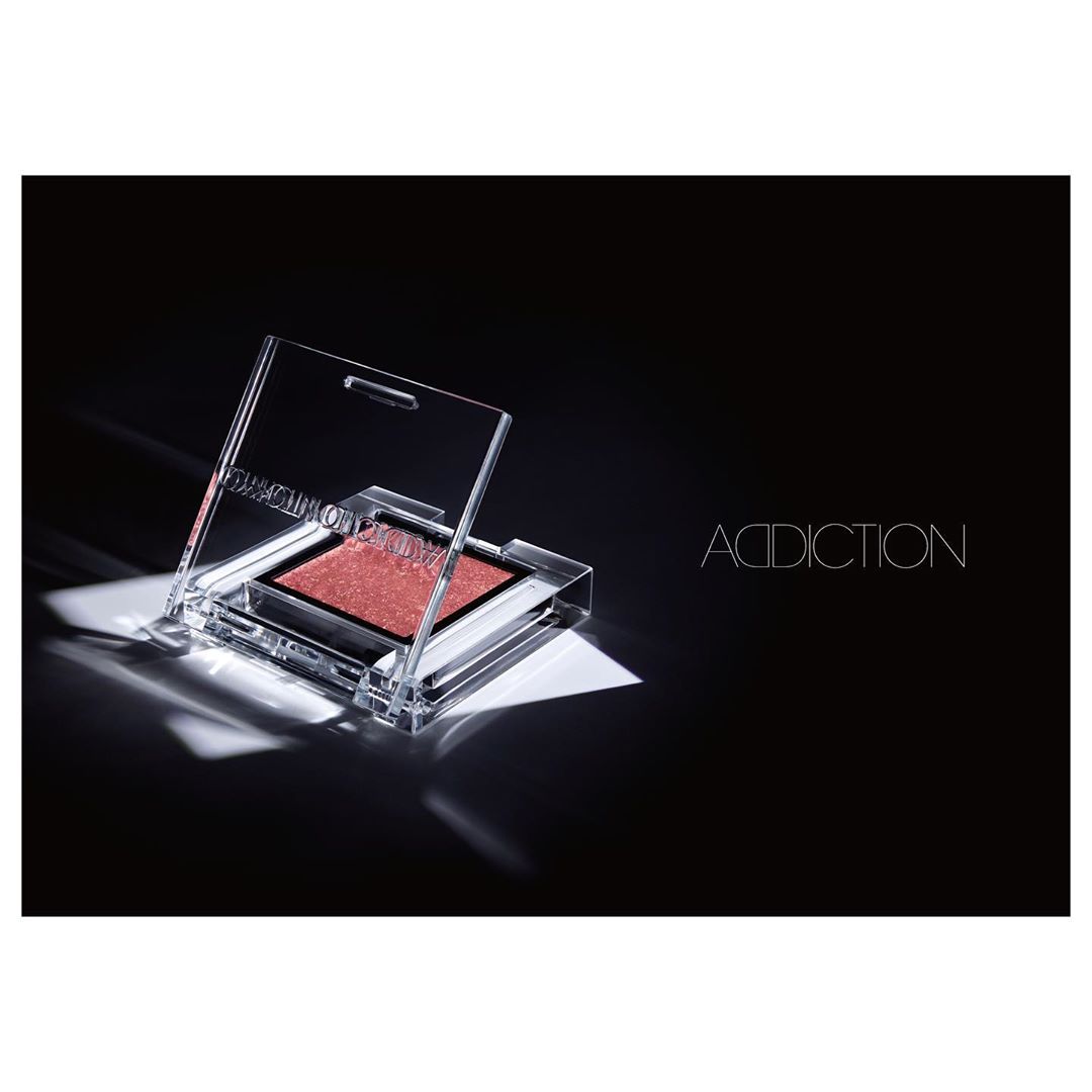 Addiction brand eyeshadow single in transparent packaging on black background with diffused lighting in a beauty and makeup product shot.
