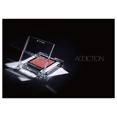 Addiction brand eyeshadow single in transparent packaging on black background with diffused lighting in a beauty and makeup product shot.