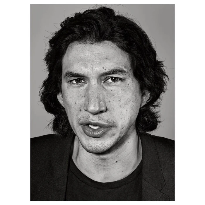 Close-up black and white portrait of actor Adam Driver looking directly at the camera with a neutral expression