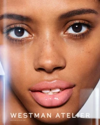 Close-up portrait of a woman with glossy pink lips, freckles, and natural makeup shot by Richard Burbridge.