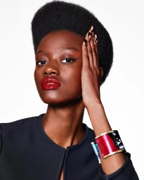 Close-up portrait of a Black woman with glossy red lips and dark hair wearing a wide patterned cuff bracelet and black top
