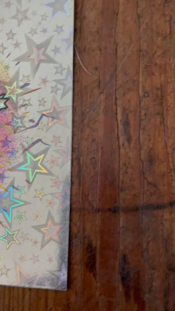 Close-up of a decorative surface with holographic stars and iridescent patterns against a dark wood background.