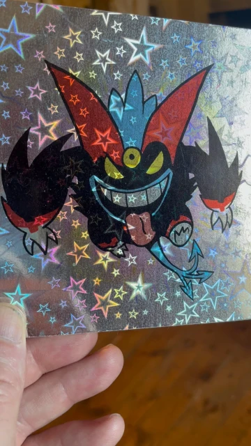 Digital illustration of a cartoon monster on a holographic background, featuring red, black, and blue colors, and star patterns.