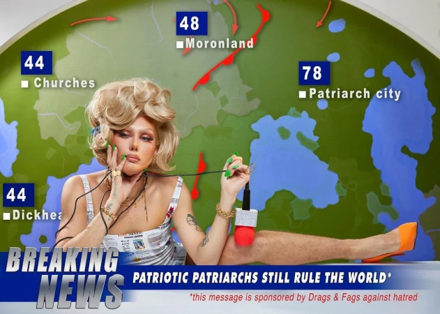 Drag performer with blonde wig poses as a news anchor in front of a map backdrop with text bubbles and political commentary.