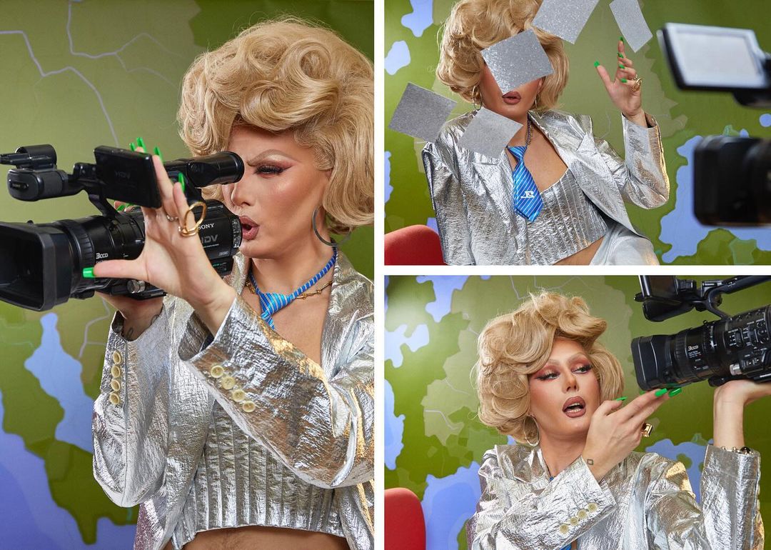 Woman with blonde wig and silver jacket films with a professional video camera in a colorful studio against a green patterned backdrop.
