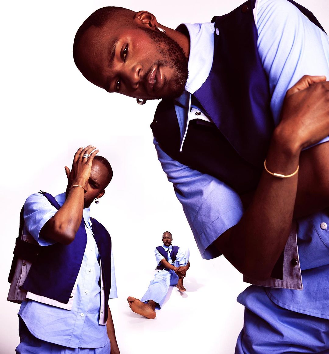 Conceptual fashion shot of an African American male model in a blue shirt and dark blue vest, multiplied against a white background.