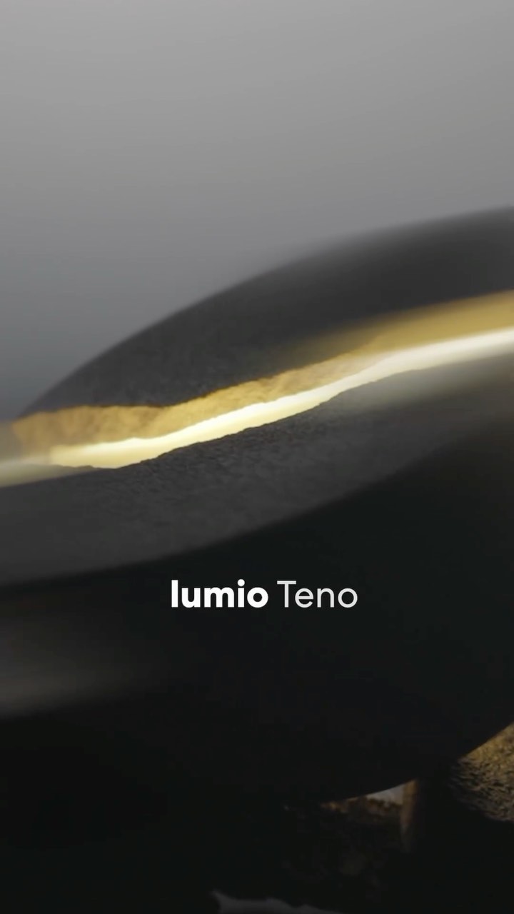 Abstract image of a dark gray sculpture with a golden or bronze streak. The background is a light gray gradient. 