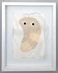 Framed mixed media artwork featuring a furry beige abstract character with googly eyes overlaid with sheer white fabric.
