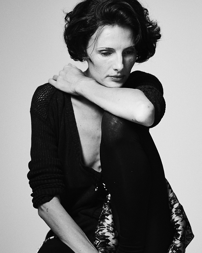 Monochrome portrait of a woman with short dark hair wearing a dark V-neck top against a plain light background