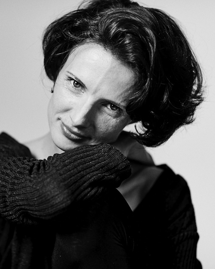 Black and white portrait of an adult woman with short dark hair and a thoughtful expression, wearing a dark, V-neck sweater.