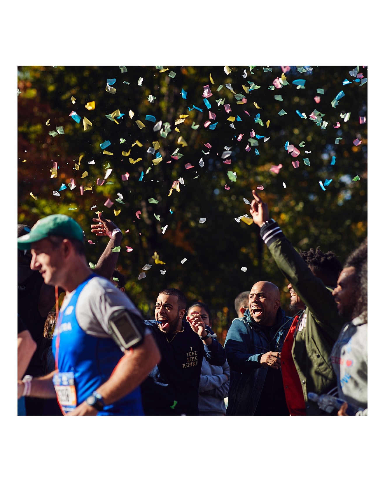 Men running a marathon, confetti falling, group of people cheering, outdoor event, sportswear, race, exercise, and healthy lifestyle.