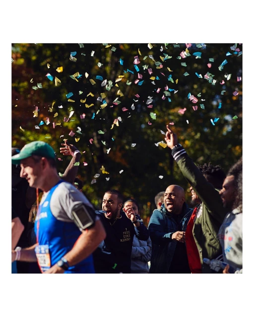 Men running a marathon, confetti falling, group of people cheering, outdoor event, sportswear, race, exercise, and healthy lifestyle.