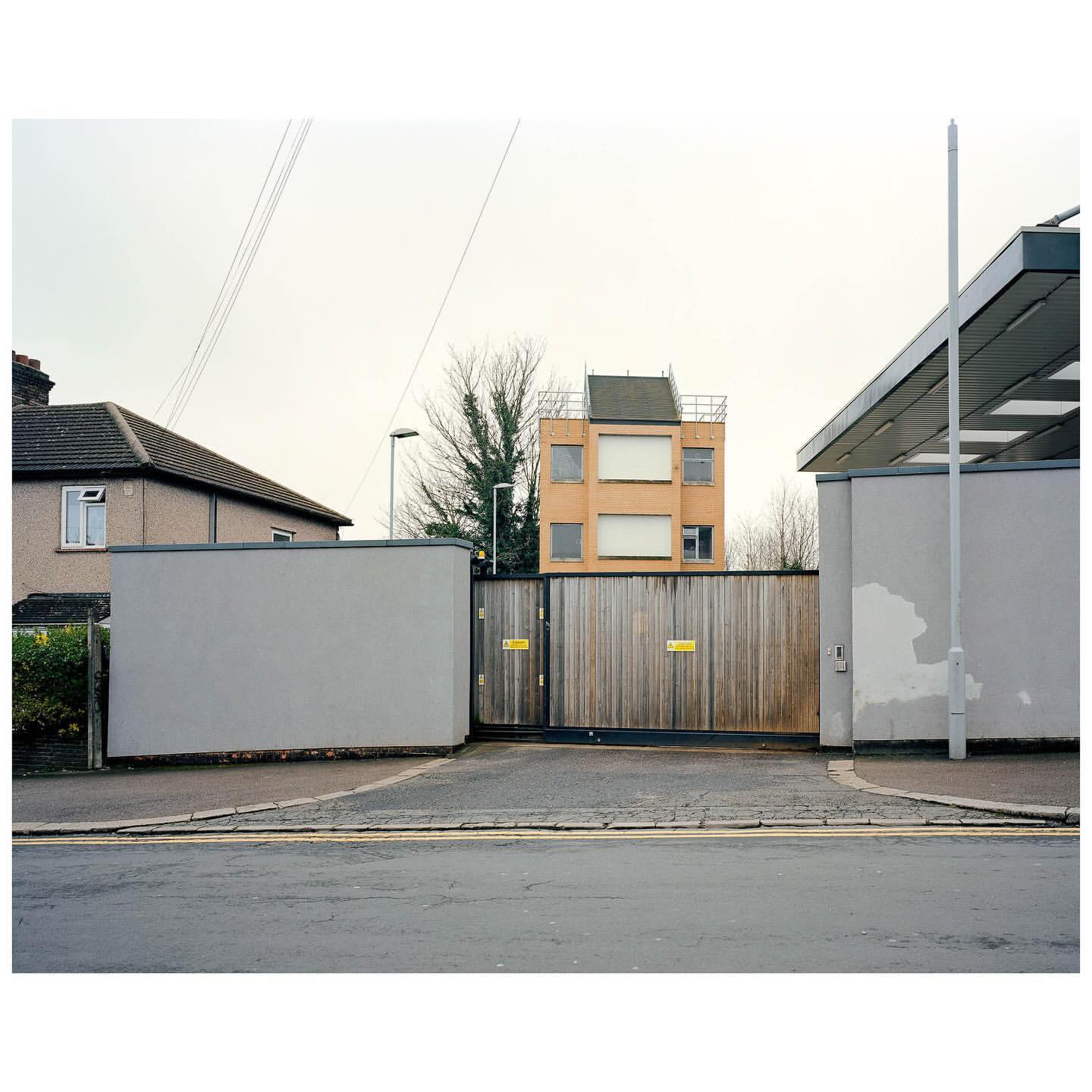 Suburban scene featuring residential architecture with a wooden gate in the foreground, creating a sense of depth and enclosure.