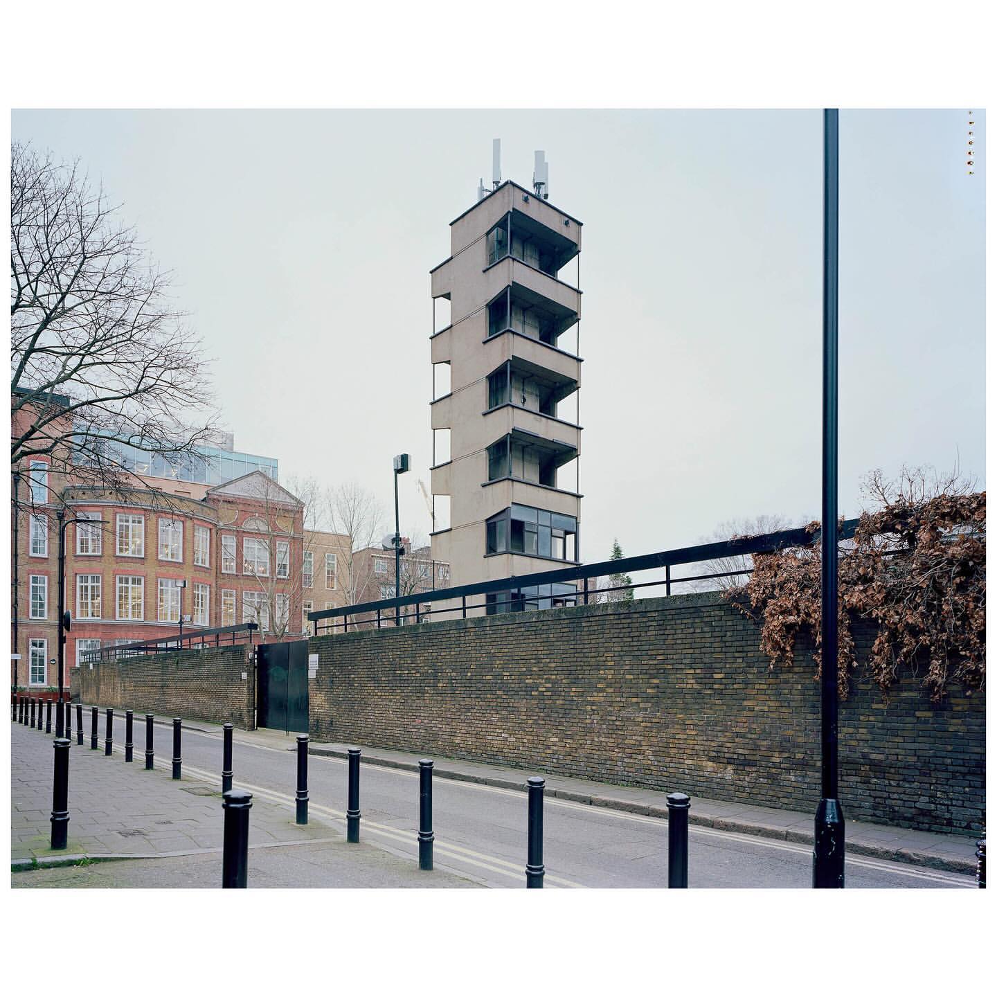 Architectural photograph of a tall concrete building with repetitive balcony elements, captured on a city street on an overcast day.