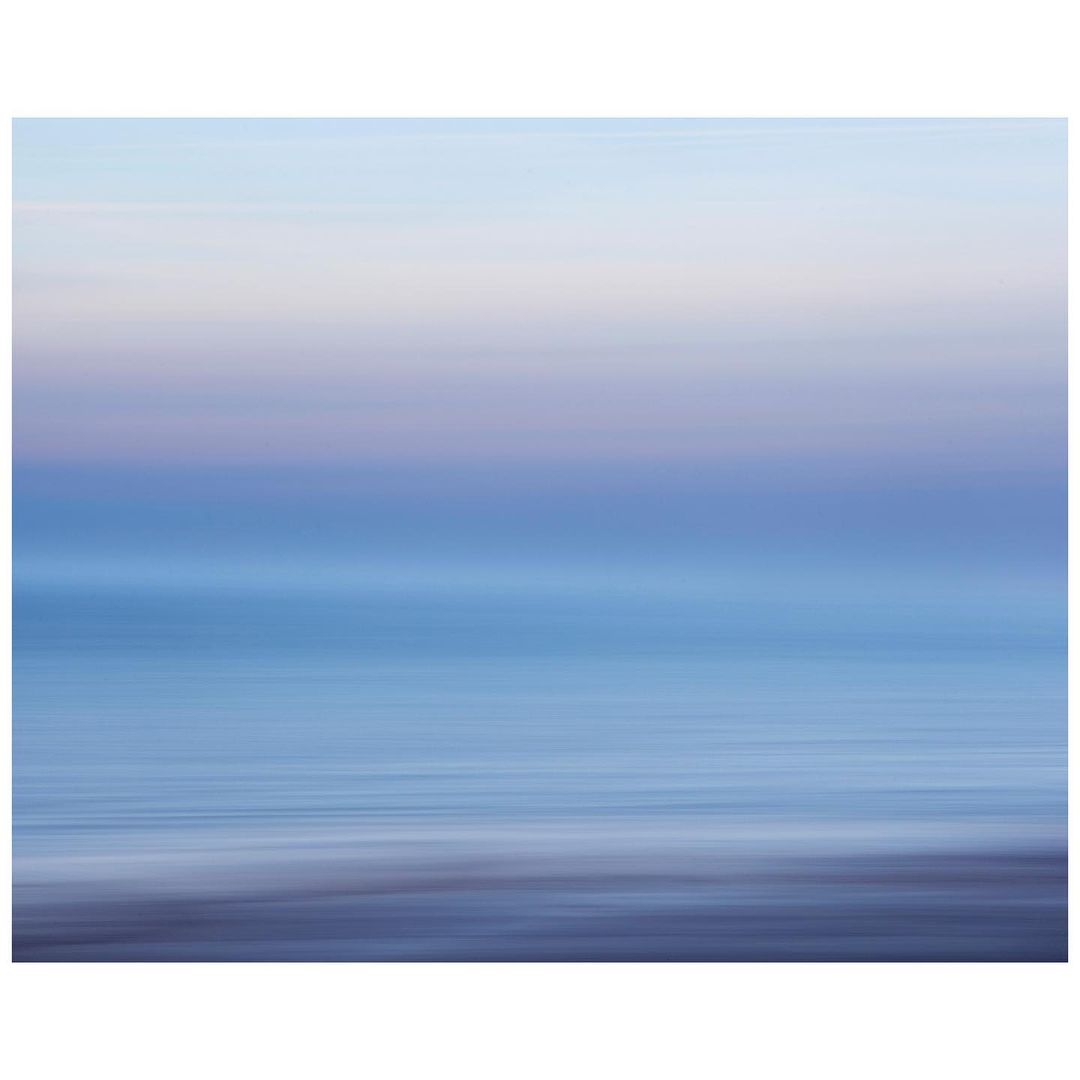 Abstract ocean and sky blend in a long exposure shot, creating a serene, dreamy seascape with smooth water and soft pastel colors.