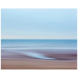 Long exposure landscape photography of a calm ocean and sandy beach under a soft horizon line by Paul Thompson.
