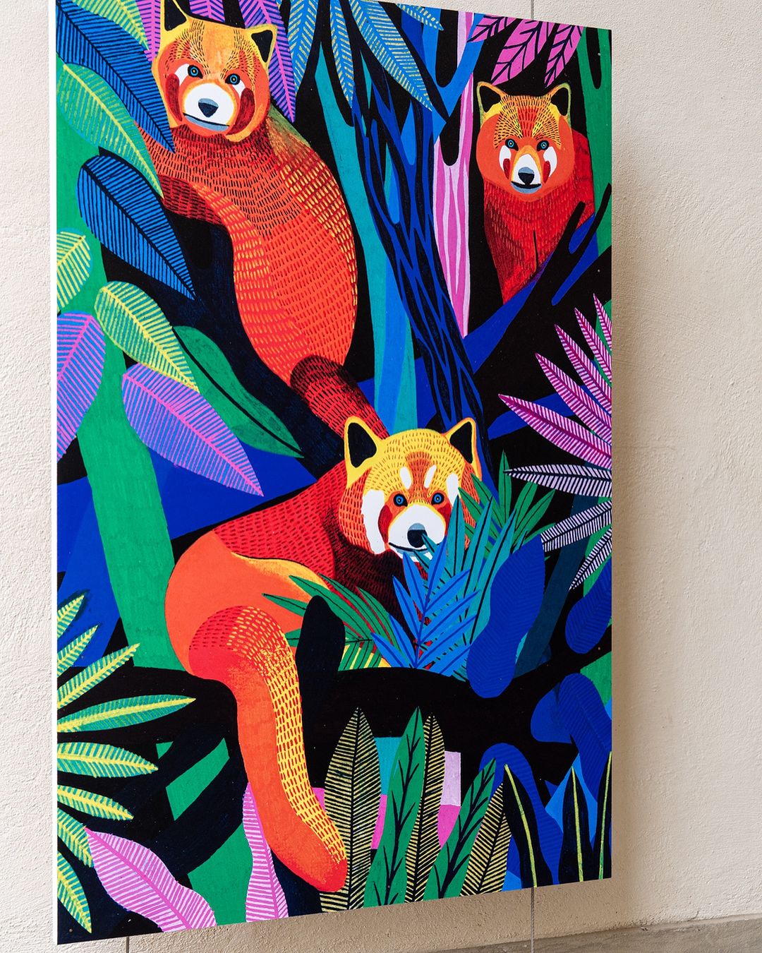 Colorful painting featuring three red pandas amidst vibrant tropical foliage with pink, green, and blue leaves against a dark background.