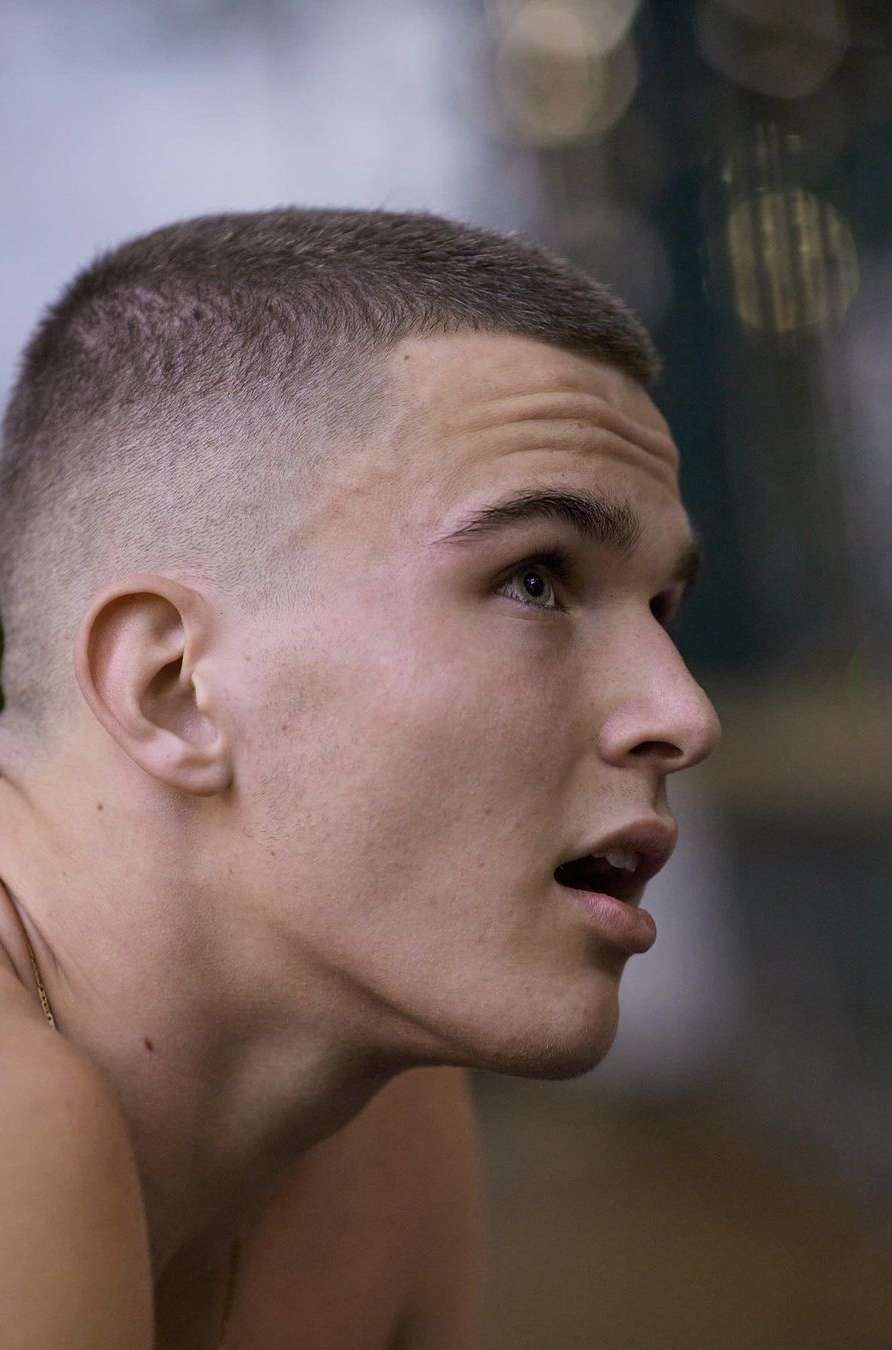Close-up shot of a young adult male with a short haircut, looking up with an open mouth in an indoor setting, focusing on his face and expression.